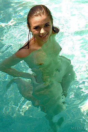Shy young girl shows her naked young body by the swimming pool